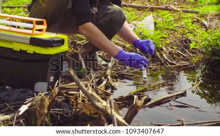 Close up hands of scientist ecologist in the forest taking sample of water in the test tube