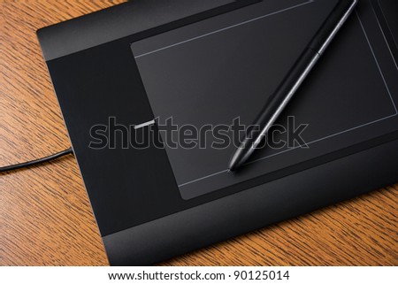 Graphic tablet on wooden table with digital pen