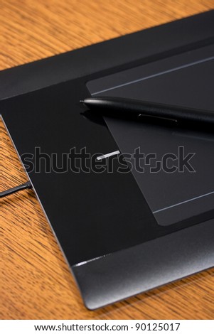 Graphic tablet on wooden table with digital pen, vertical