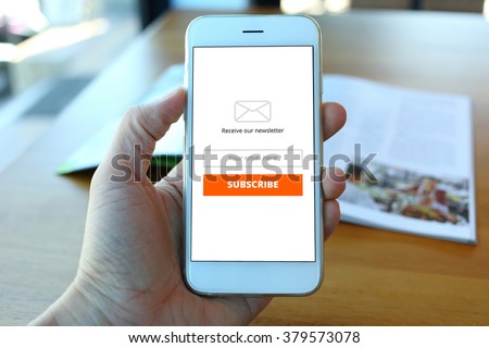 Hand holding smartphone with receive newsletter form on cafe background