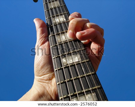 Electric guitar neck against blue sky background.