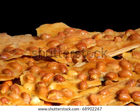 Close view of peanut brittle against black background.