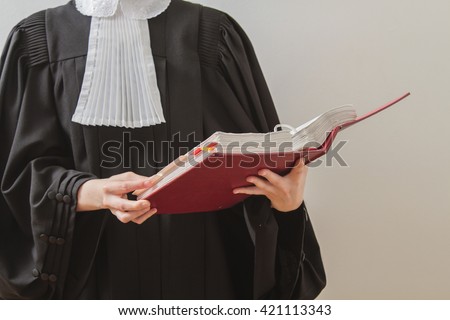 canadian lawyer in toga, reading from a red law book