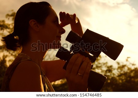 Young woman holding binoculars and watching a beautiful sunset, Sunset, photography