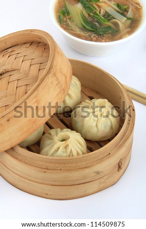 Chinese Steamed vegeterian steamed dumplings dimsum in  bamboo steamer. With traditional asian soup