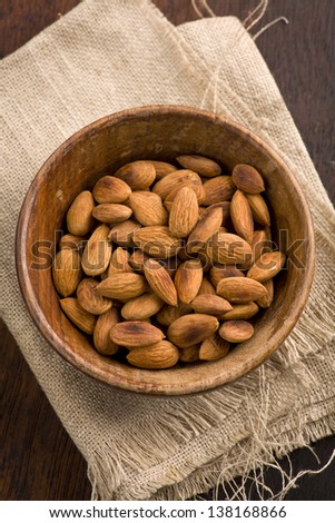 roasted almonds in a wooden bowl on wooden background