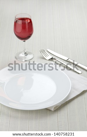 Place setting with white plates and red wine