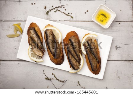 Fish, Spanish tapas - sprat with lemon on baked bread