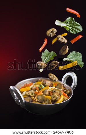 Chinese stir fry vegetables with ingredients flying around. With space for copy