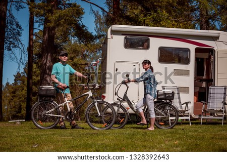 Woman with a man on electric bike resting at the campsite. Family vacation travel, holiday trip in motorhome RV, Caravan car Vacation.