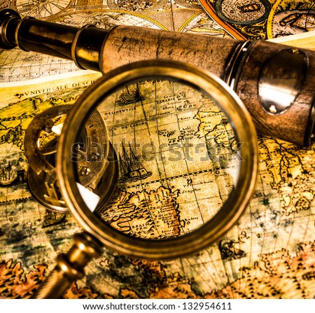 Vintage magnifying glass, compass, telescope lying on an old map.