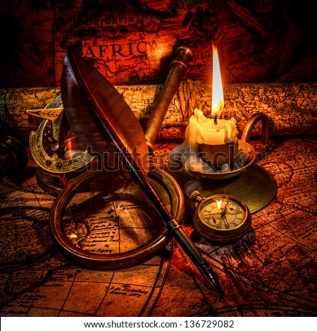 Vintage compass, magnifying glass, pocket watch, quill pen, spyglass lie on an old ancient map with a lit candle. Vintage still life.