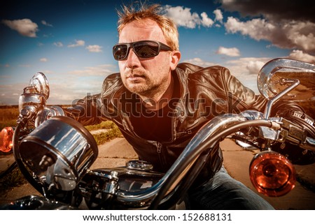 Biker in sunglasses and leather jacket racing on the road