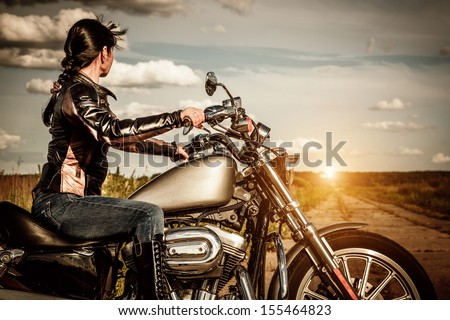 Biker Girl In A Leather Jacket On A Motorcycle Looking At The Sunset.