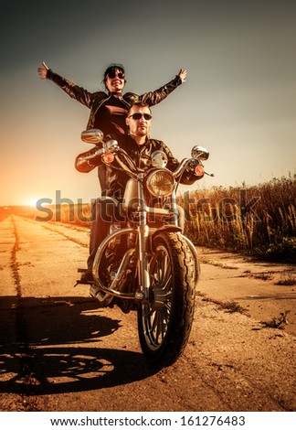Couple Bikers In A Leather Jacket Riding A Motorcycle On The Road