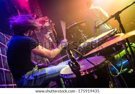 Drummer (blurred motion) playing on drum set on stage. Focus on the drum and microphone.