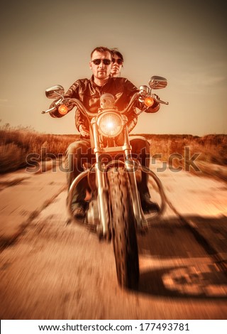 Couple Bikers in a leather jacket riding a motorcycle on the road