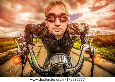 Funny Biker in sunglasses and leather jacket racing on the road (fisheye lens). Filter applied in post-production.