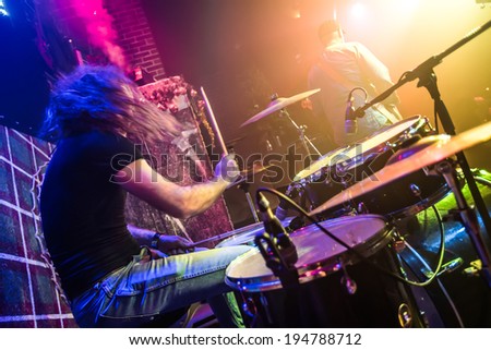 Drummer (blurred motion) playing on drum set on stage. Focus on the drum and microphone.