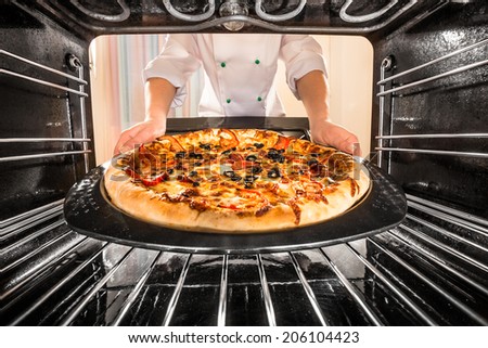 Chef prepares pizza in the oven, view from the inside of the oven. Cooking in the oven.