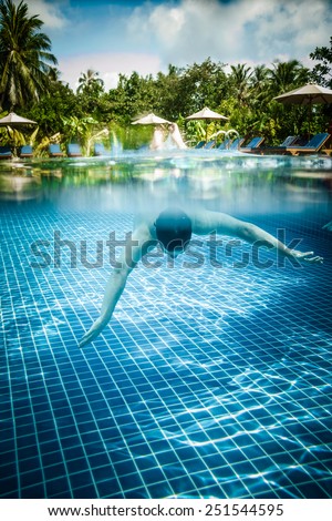 Man dives into a swimming pool views over the water and under water. Maldives.