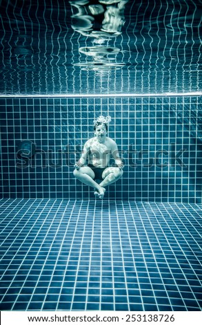Man under water in a swimming pool to relax in the lotus position