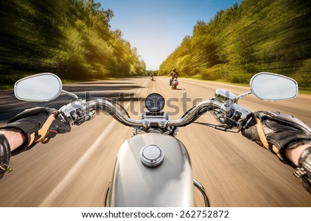 Biker driving a motorcycle rides along the asphalt road. First-person view.