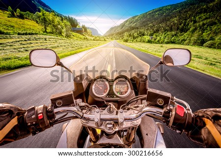 Biker driving a motorcycle rides along the asphalt road. First-person view.