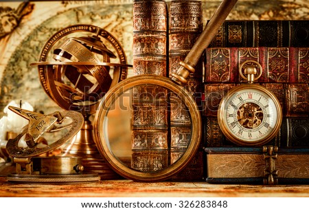 Vintage still life. Vintage magnifying glass lies, pocket watch, old book and astrolabe on an ancient world map in 1565.