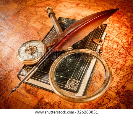Vintage still life - magnifying glass, pocket watch, old book and goose quill pen lying on an old map in 1565.