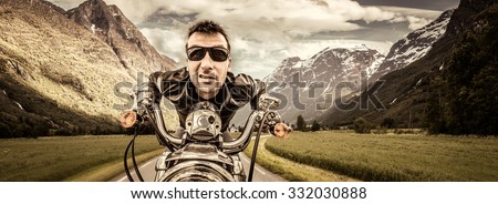 Funny Biker in sunglasses and leather jacket racing on mountain serpentine. Filter applied in post-production.