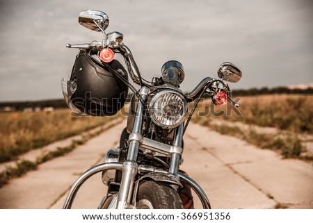 Motorcycle on the road with a helmet on the handlebars.