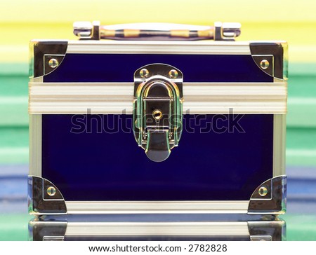 Dark blue steel small suitcase with the lock on a multi-coloured background.