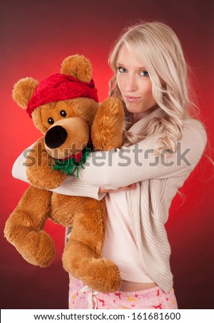 Beautiful young woman holding a Christmas teddy bear