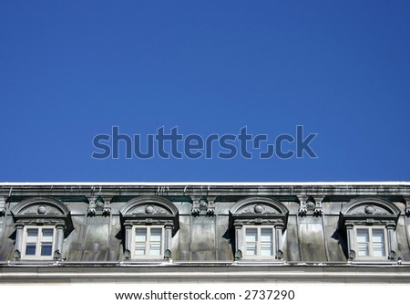 old grey dormer window with blue sky