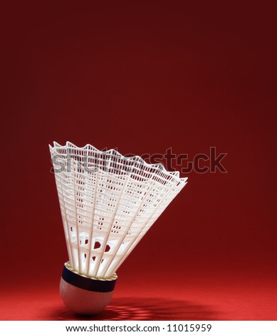 nylon badminton shuttlecock with its shadow, red background
