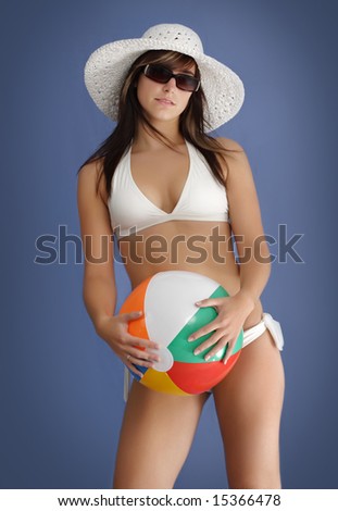 young woman wearing white bikini and hat, holding a beach ball
