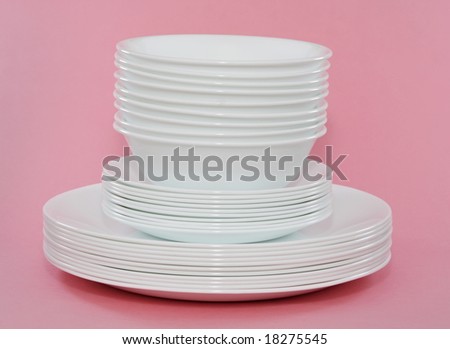 white bowls and plates stacked, pink background