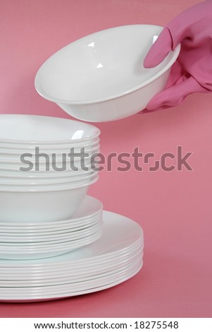 white bowls and plates stacked, pink background