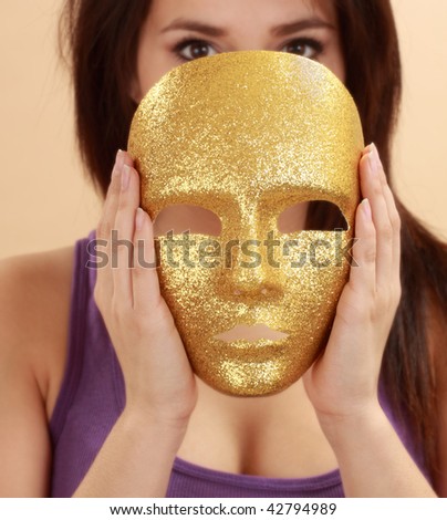 beautiful hispanic young woman holding a gold mask
