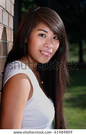 outdoor portrait of a beautiful young asian woman near brick wall