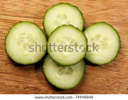 sliced english cucumber on wood plank, top view