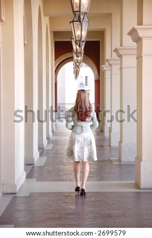 a girl walking in a hallway with her back turned to camera