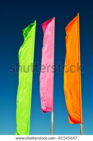 flags - green, pink, orange against the blue sky