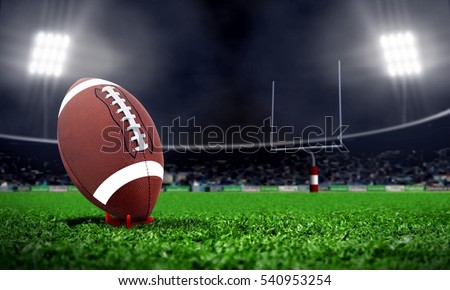 American football in stadium at night with spotlight