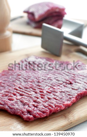 Raw beef round steak and meat pounder