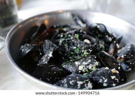 Mussels with garlic sauce and black pasta in frying pan