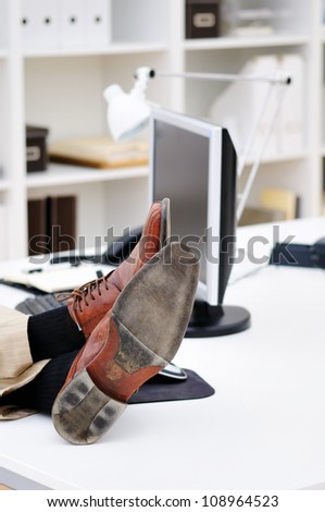 Relax in office scene with legs in old shoes on the table