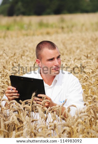 Young biologist in the field takes notes about scientific experiment in the wheat field