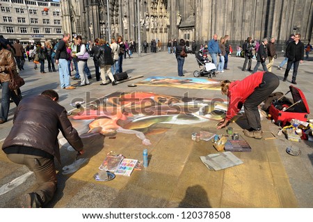COLOGNE, GERMANY-APRIL 10: Unidentified street artists make a beautiful painting on a pavement on front of the cathedral on April 10, 2010 in Cologne.